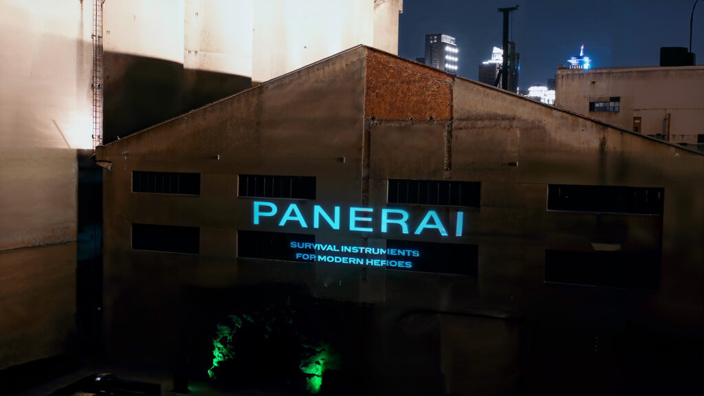 Logo Panerai projeté sur une façade industrielle à Shanghai, avec slogan brandé dans un cadre nocturne.